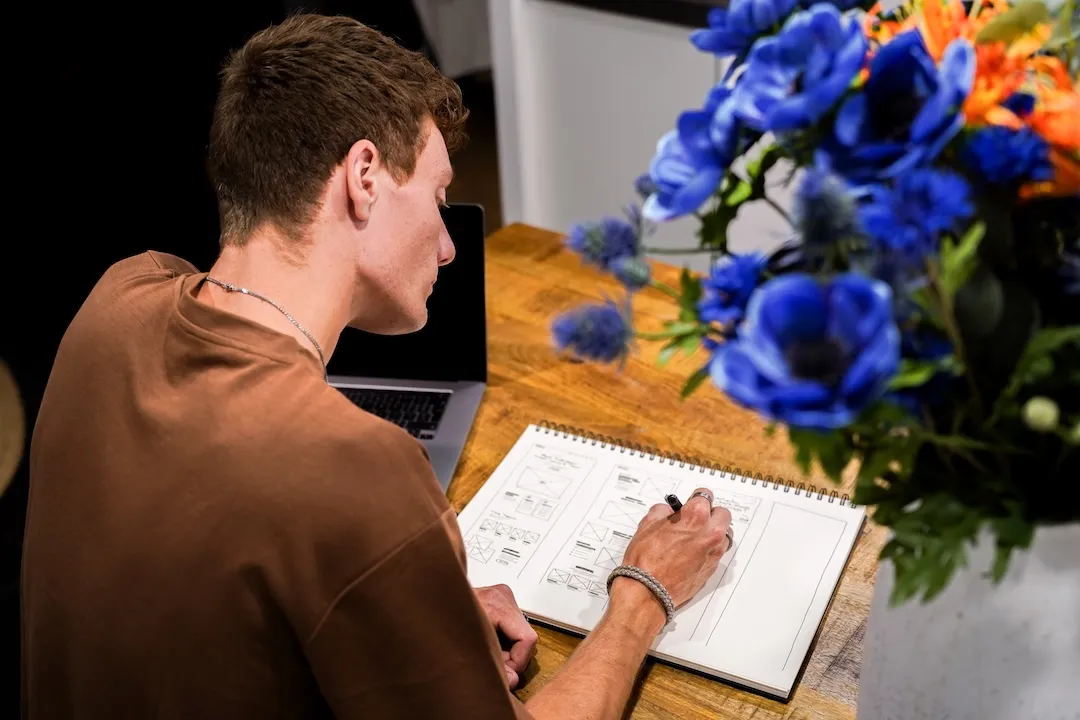 Foto van man die schets in een kladblok