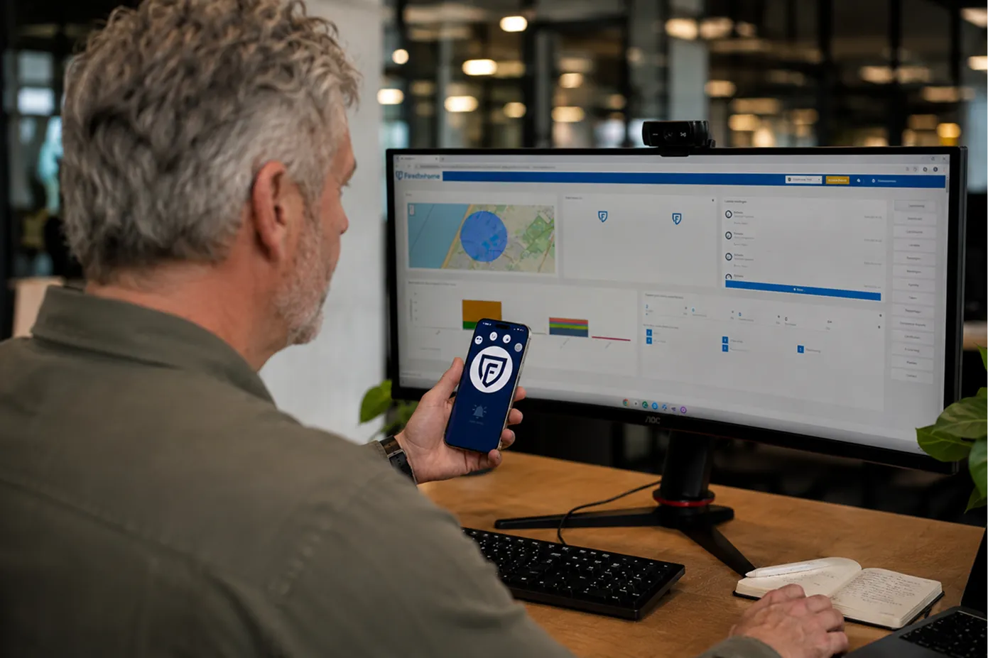 Man achter het Findwhere dashboard op zijn monitor en heeft de Findwhere BHV-App in zijn hand.