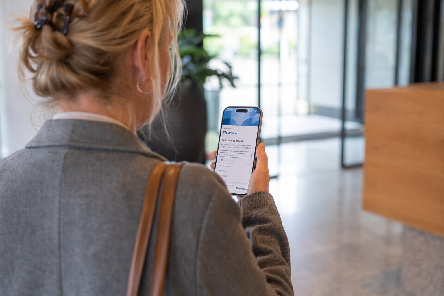 Vrouw meld zich aan met telefoon met Findwhere bezoekerregistratie